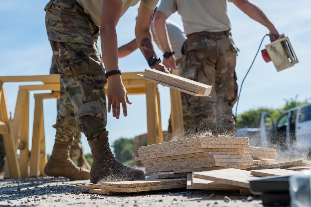 An Airman from the 23d Civil Engineer Squadron stacks wood, June 1, 2019, in Sainte-Mère-Église, France. The engineers provided structural support for the Commemoration of D-Day 75 by repairing and building bridges that were used to access hard-to-reach areas of a parachute drop zone. As part of the commemoration, parachutists from across the Department of Defense performed the same jumps their predecessors did on D-Day. (U.S. Air Force photo by Airman 1st Class Hayden Legg)