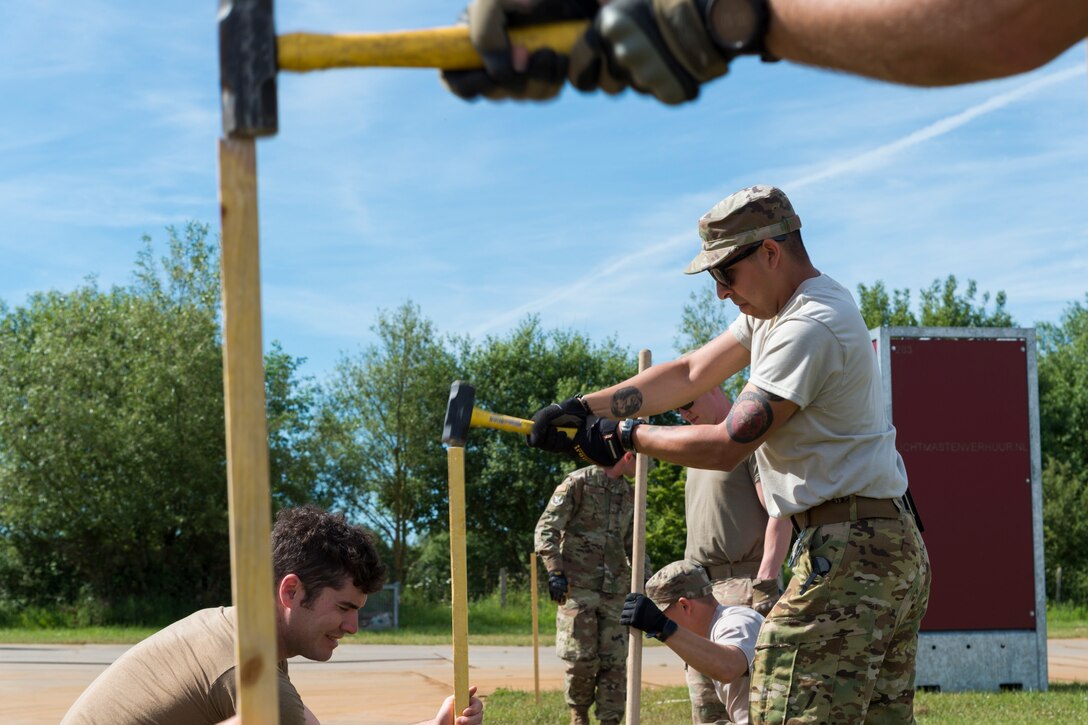 Airman 1st Class Jesse Vega, 23d Civil Engineer Squadron electrical power production engineer, drives a stake into the ground, June 2, 2019, near Sainte-Mère-Église, France. The engineers provided structural support for the Commemoration of D-Day 75 by repairing and building bridges that were used to access hard-to-reach areas of a parachute drop zone. As part of the commemoration, parachutists from across the Department of Defense performed the same jumps their predecessors did on D-Day. (U.S. Air Force photo by Airman 1st Class Hayden Legg)