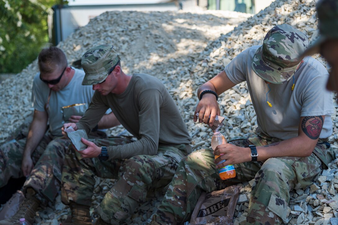 Airmen from the 23d Civil Engineer Squadron prepare Meals, Ready-to-Eat, June 1, 2019, in Sainte-Mère-Église, France. The engineers provided structural support for the Commemoration of D-Day 75 by repairing and building bridges that were used to access hard-to-reach areas of a parachute drop zone. As part of the commemoration, parachutists from across the Department of Defense performed the same jumps their predecessors did on D-Day. (U.S. Air Force photo by Airman 1st Class Hayden Legg)