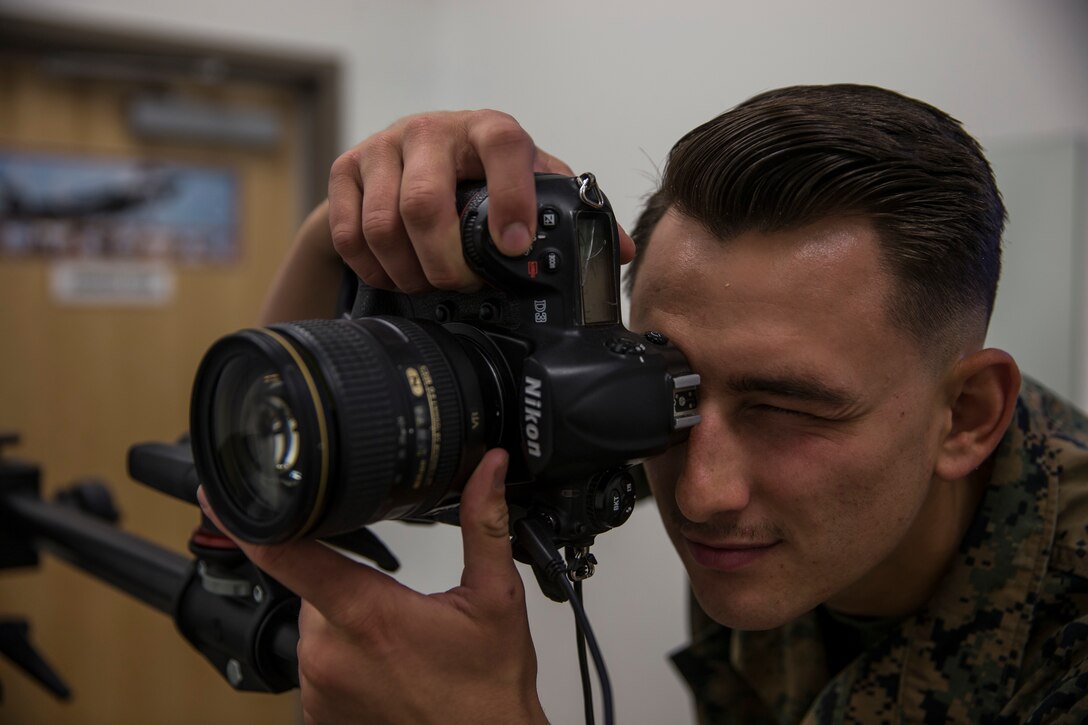 U.S. Marine Corps Lance Cpl. John Hall, a combat photographer assigned to Marine Corps Air Station (MCAS) Yuma, takes a picture in the promotion photo studio at MCAS Yuma, Ariz., June 17, 2019. As a combat photographer, Hall supports Marines aboard MCAS Yuma by taking promotion, re-enlistment, and command photos when needed. (U.S. Marine Corps photo by Sgt. Isaac D. Martinez)