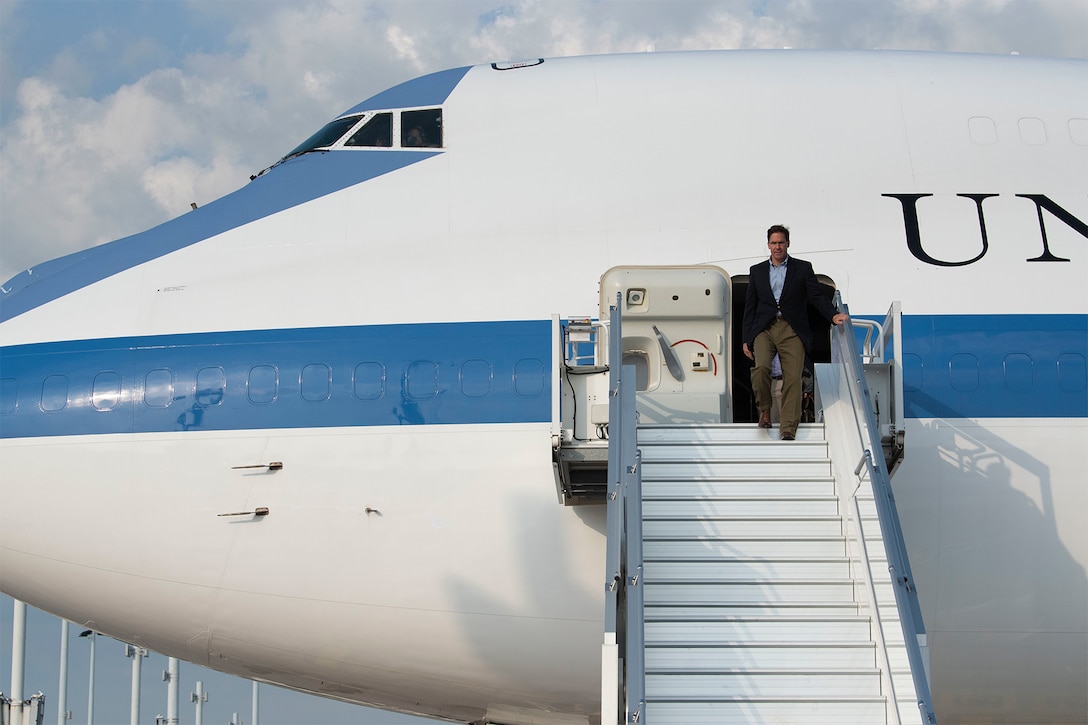Acting Defense Secretary Mark T. Esper walks down steps out of an aircraft.