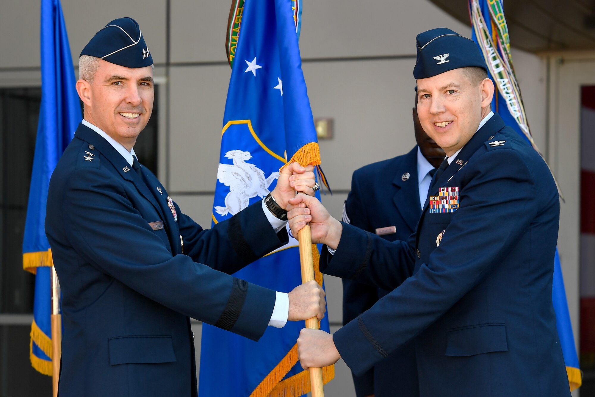 Maj. Gen. Stephen Whiting, Fourteenth Air Force commander, passes the guidon to Col. James Smith, 50th Space Wing commander, during a change of command ceremony in front of the DeKok building at Schriever Air Force Base, Colorado, June 24, 2019. Smith comes to the 50th SW from Air Force Element, RAF Menwith Hill, United Kingdom. (U.S. Air Force photo by Kathryn Calvert)