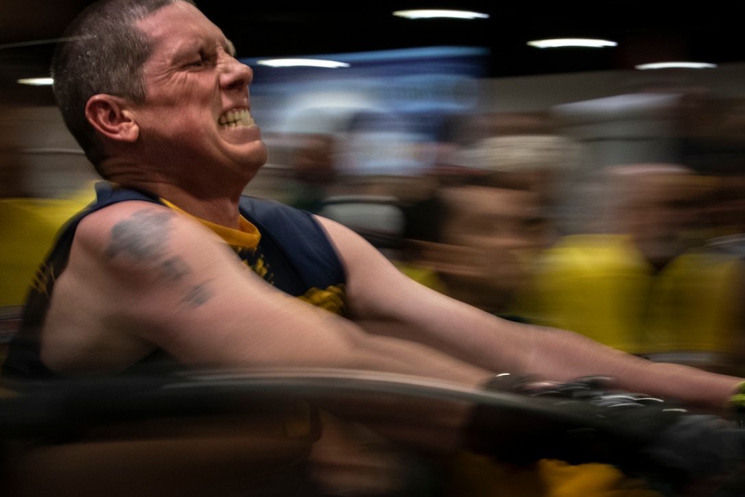 A military athlete grimaces as he takes part in a rowing competition.