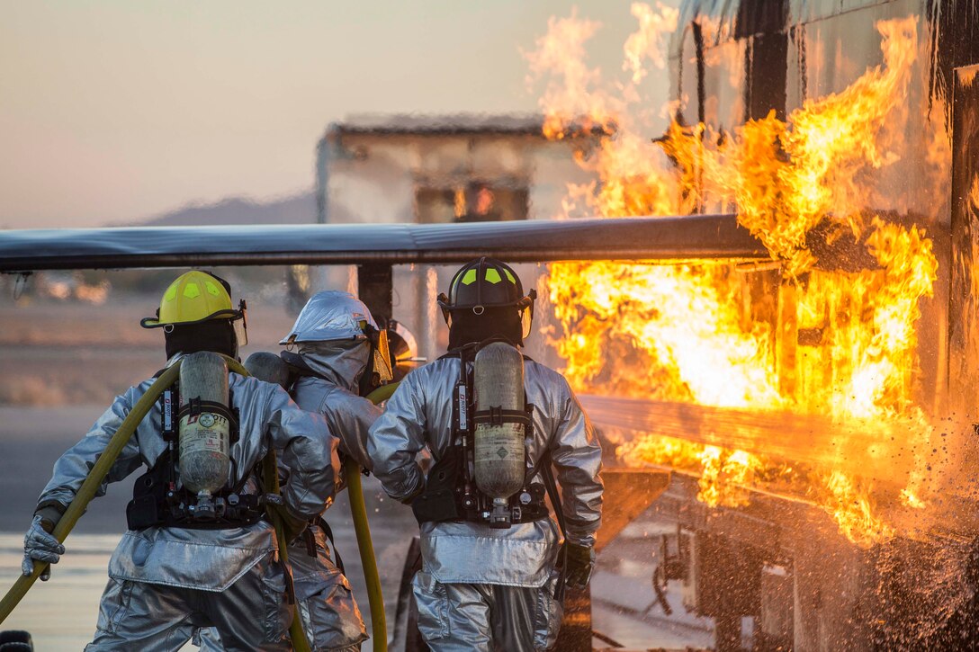 Marines use a hose to extinguish a fire.