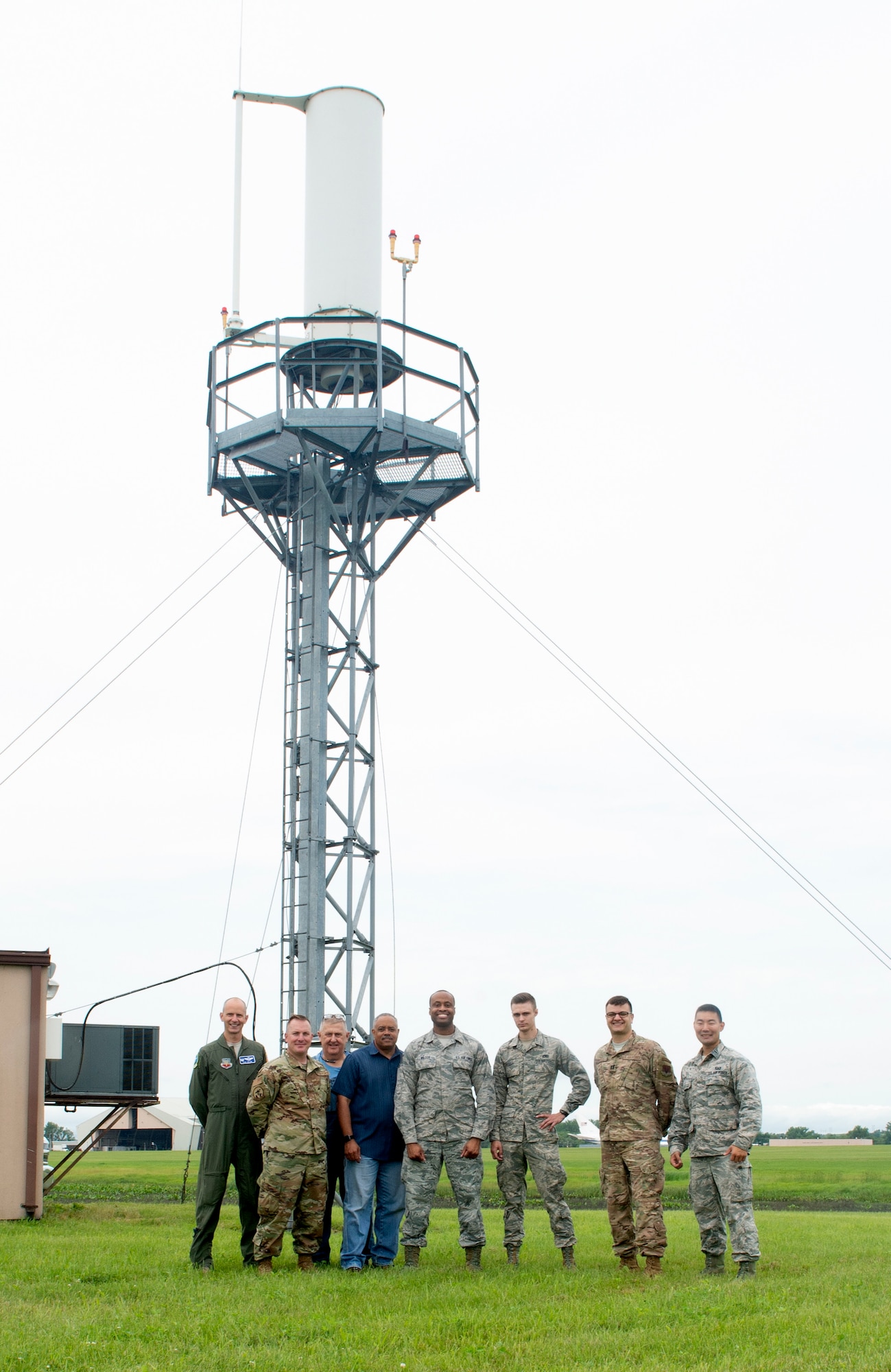 The Tactical Air Navigational System repair team pose for group photo in front of TACAN antenna June 22, 2019, at Offutt Air Force Base, Nebraska. They removed damaged components, replacing them and aligning the system and performing peak tuning to optimize electronics in preparation for the Federal Aviation Administration to certify newly installed system. (U.S. photo by L. Cunningham)