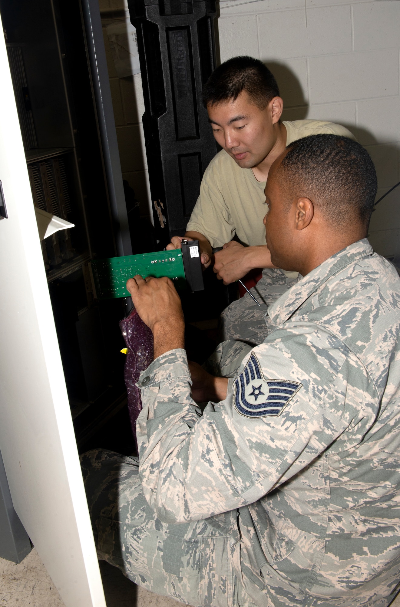 Tech. Sgt. Torrey Wilcox, right, 55th Operations Support Squadron Radar Airfield Weather Systems NCO in charge, and 1st Lt. Cody Park, center, 55th OSS, Airfield Operations Flight director of operations, dismantle and repackage damaged components from a Tactical Air Navigation System rack damaged by flood waters in March on June 22, 2019, at Offutt Air Force Base, Nebraska. The damaged components will be shipped back to the Thales Company to be refurbished. (U.S. photo by L. Cunningham)