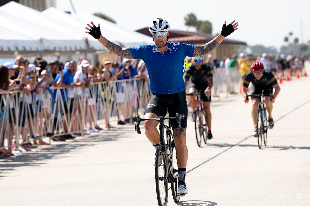 A man on a bicycle throws his arms out after crossing a finish line.