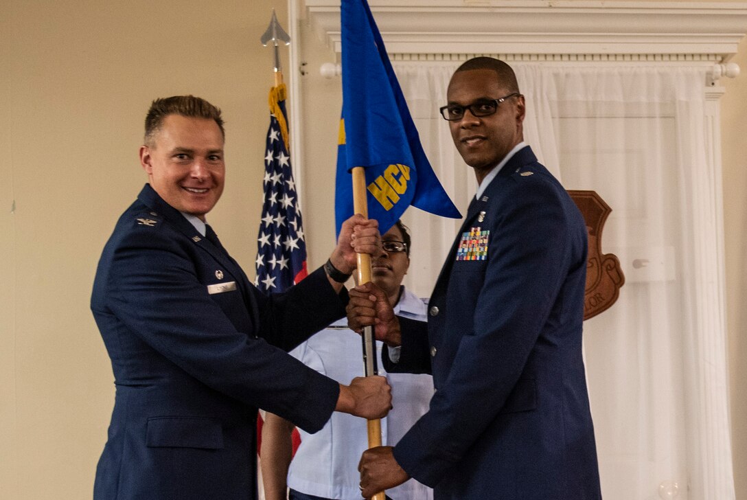 U.S. Air Force Col. Christian Lyons, 20th Medical Group commander, left, hands the guidon to Lt. Col. Jamale Hart, incoming 20th Healthcare Operations Squadron commander, at Shaw Air Force Base, South Carolina, June 21, 2019.