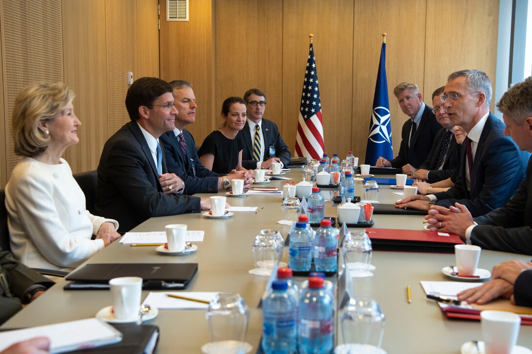 A group of men and women speak to each other around a table.