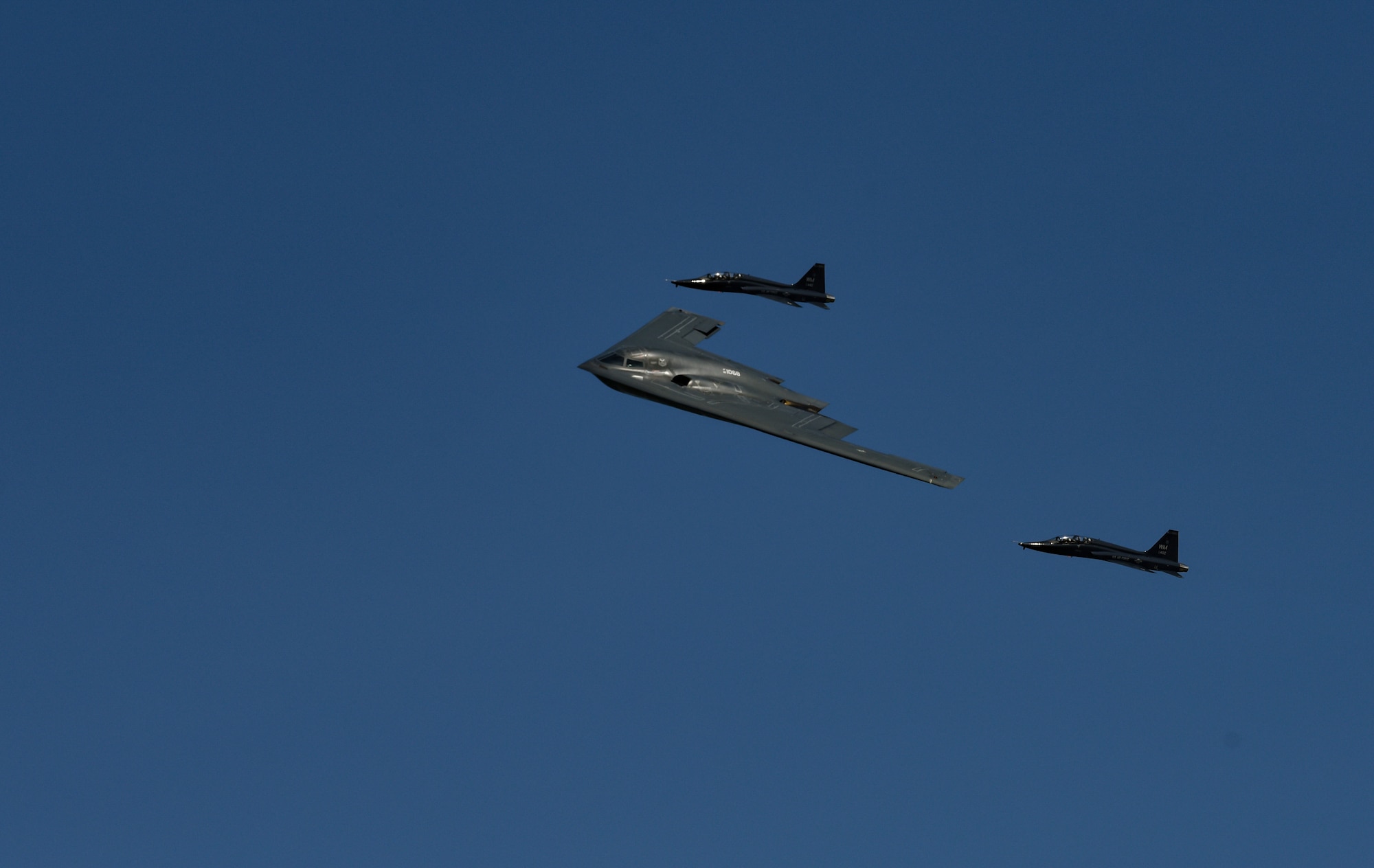 A B-2 Spirit is flanked by two T-38 Talons for a  formation flyover maneuver during the 2019 Wings over Whiteman Air & Space Show at Whiteman Air Force Base, Missouri, June 15, 2019. The T-38 is a crucial asset utilized to maintain airmanship and tactics for B-2 pilots. Every B-2 pilot is also a qualified T-38 pilot. (U.S. Air Force photo by Tech. Sgt. Alexander W. Riedel)