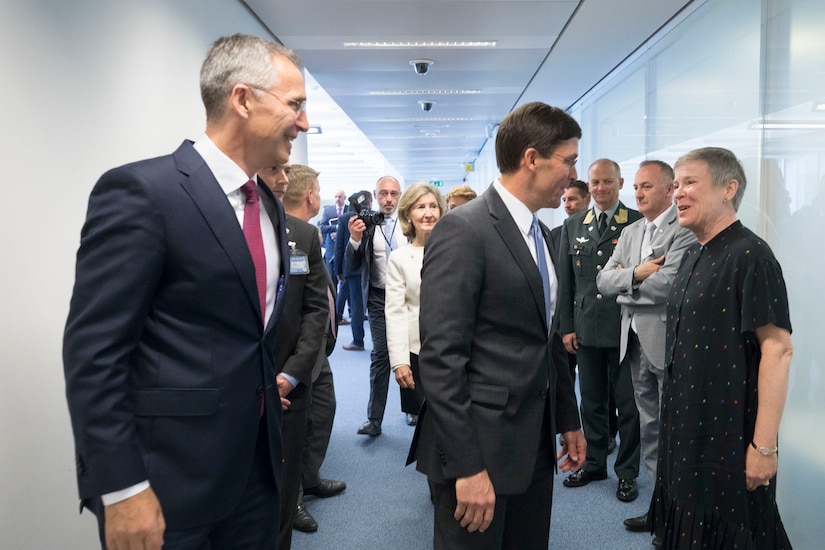 A man speaks to a woman in a hallway.