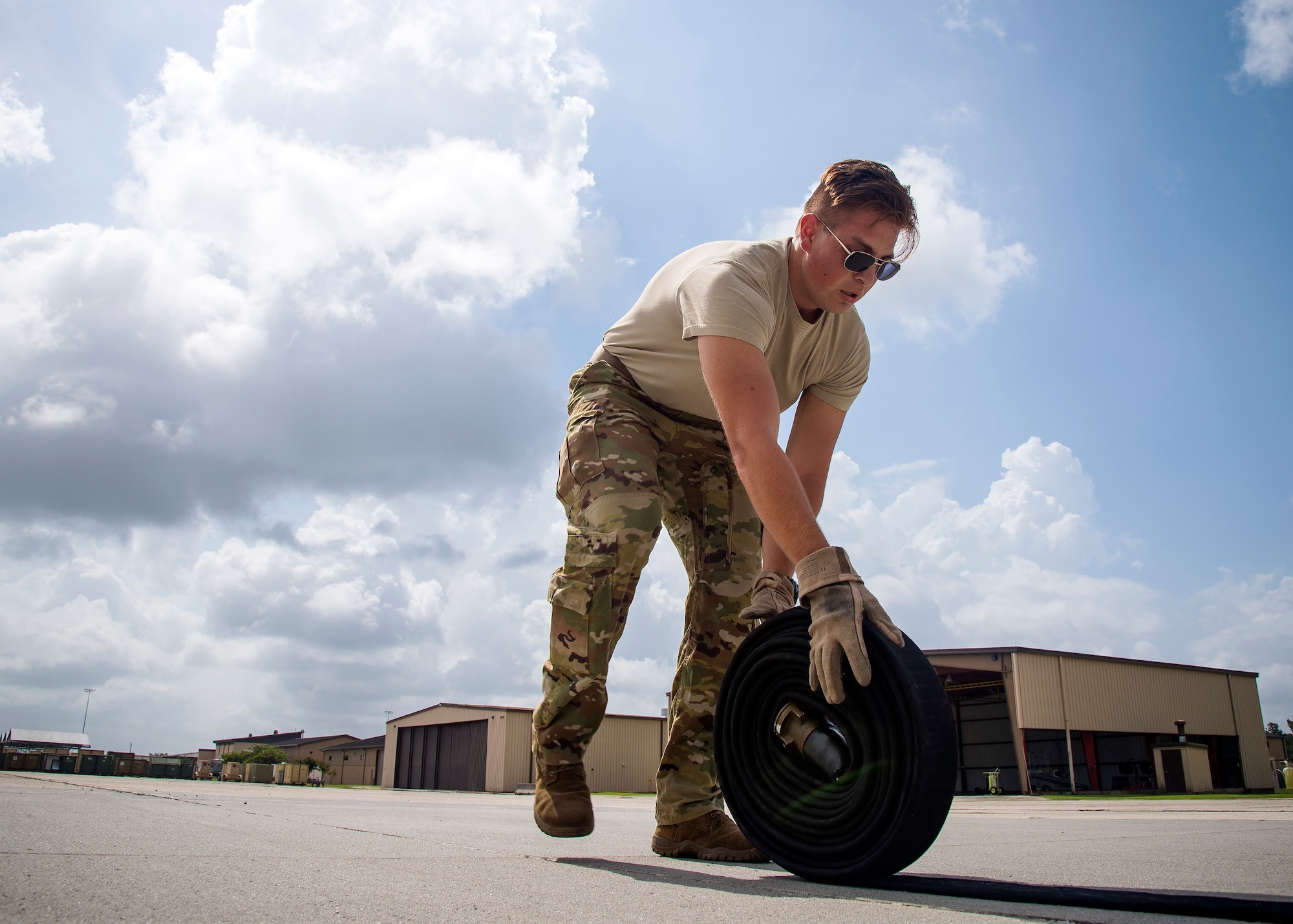 Senior Airman Sam Neas, 71st Rescue Squadron loadmaster, rolls up a fuel line hose during Forward Area Refueling Point (FARP) team tryouts, June 21, 2019, at Moody Air Force Base, Ga. Neas participated to better understand the 23d Logistics Readiness Squadron’s FARP team of elite fuels special operators whose mission is to provide needed fuel to aircraft in any environment in a swift manner. This greatly extends the reach of the personnel recovery mission by increasing options and ensuring safety for the rescue community. (U.S. Air Force photo by Airman 1st Class Eugene Oliver)