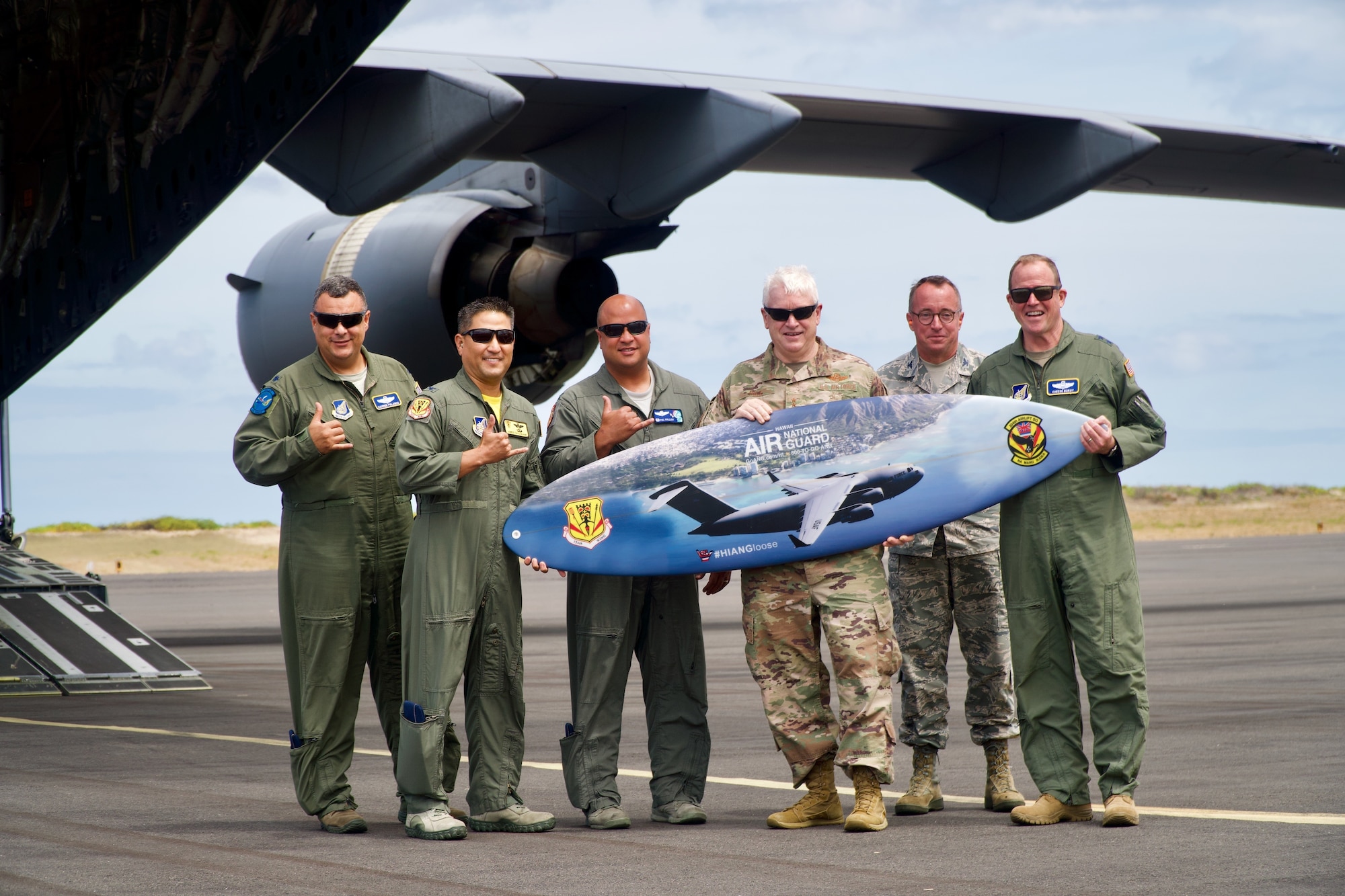 Left to right, Lt. Col. Jhonny Polanco, Deputy Director ANG Forces, HQ PACAF, Col. James Shigekane, Vice Commander, 154th Wing, Col. Phillip Mallory, Commander, 298th Air Defense Group, Lt. Gen. L. Scott Rice, Director of the Air National Guard, Col. Dann Carlson, Director A5/8, HQ HIANG, Maj. Gen. David Burgy, Air National Guard Assistant to COMPACAF poses for a photo with the 204th Airlift Squadron surfboard on June 21, 2019 at Barking Sands, Kauai.