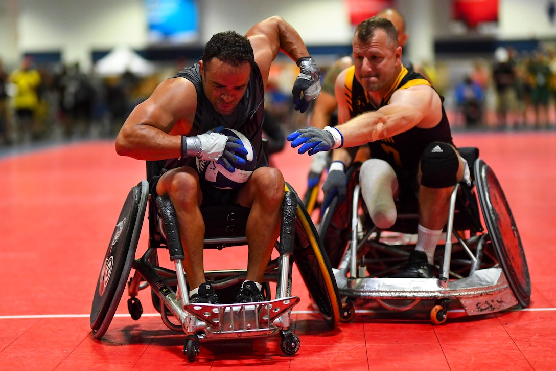 Two men in wheelchairs play rugby.