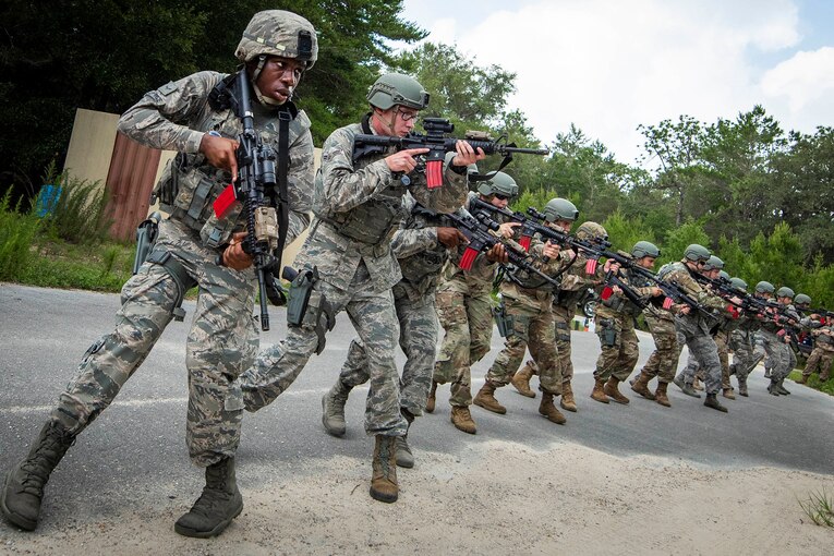 a group of airmen stand in a line holding up weapons.