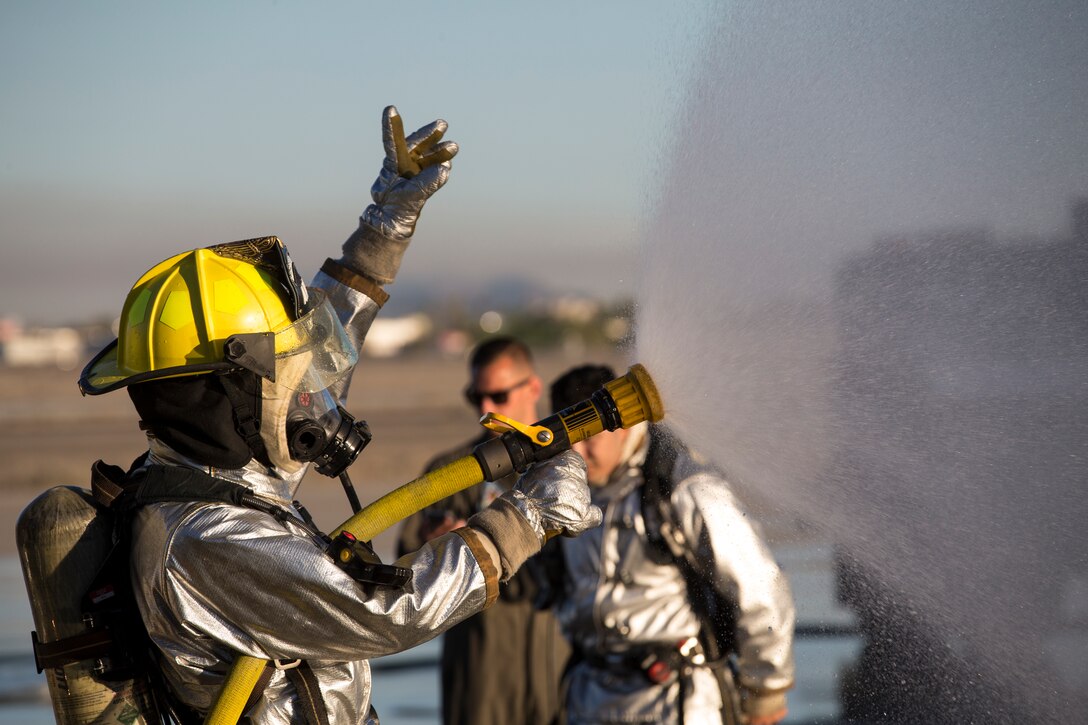 U.S. Marines with Aircraft Rescue and Firefighting (ARFF), Headquarters and Headquarters Squadron (H&HS), Marine Corps Air Station (MCAS) Yuma conduct hand line drills during live burn training on MCAS Yuma, Ariz., June 25, 2019. Hand line drills focus on techniques to push fuel fires away from aircraft, ARFF Marines train monthly to enhance their readiness when responding to emergencies on the flight line. (U.S. Marine Corps photo by Sgt. Allison Lotz)