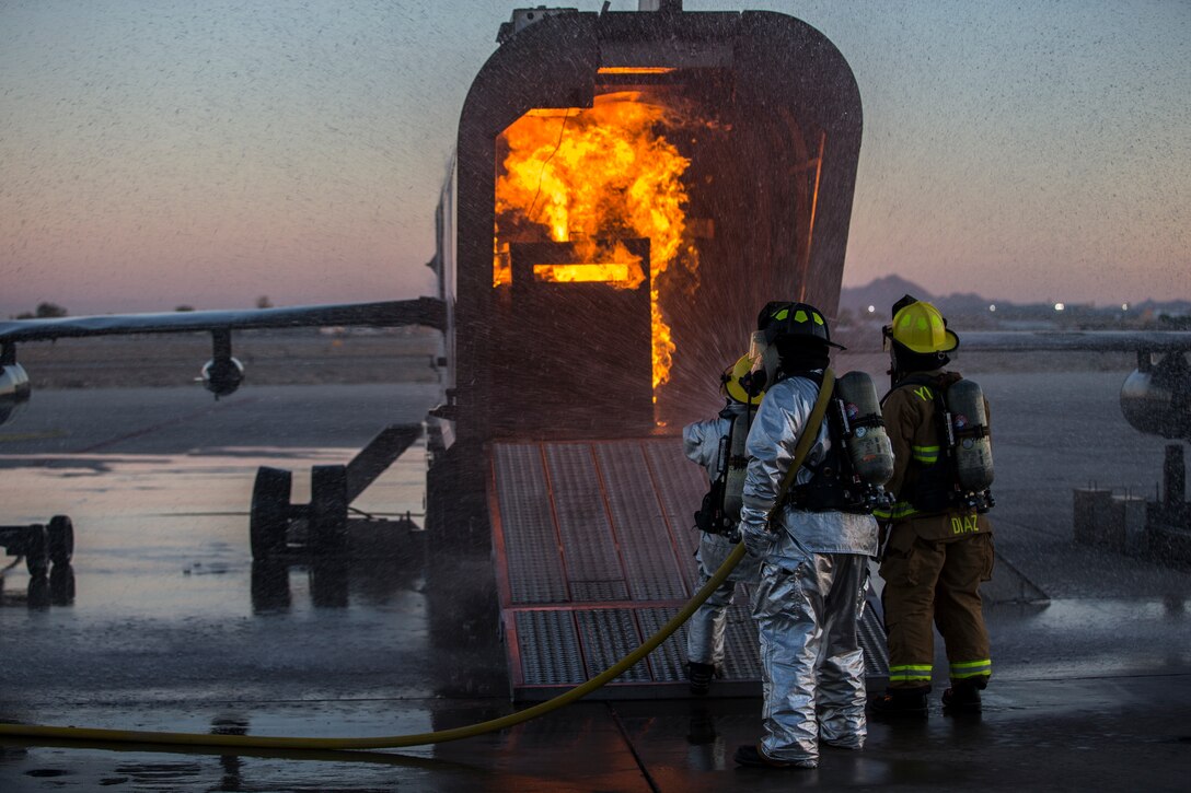 U.S. Marines with Aircraft Rescue and Firefighting (ARFF), Headquarters and Headquarters Squadron (H&HS), Marine Corps Air Station (MCAS) Yuma conduct hand line drills during live burn training on MCAS Yuma, Ariz., June 25, 2019. Hand line drills focus on techniques to push fuel fires away from aircraft, ARFF Marines train monthly to enhance their readiness when responding to emergencies on the flight line. (U.S. Marine Corps photo by Lance Cpl. John Hall)