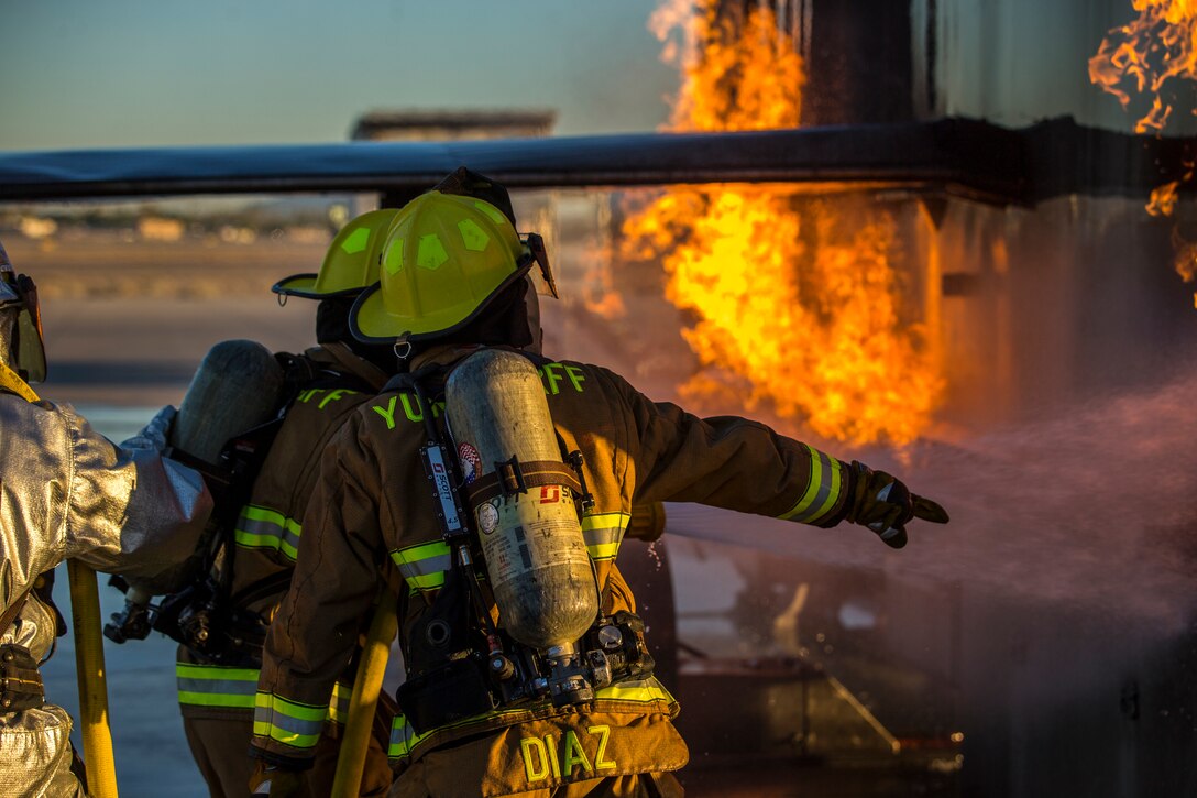 U.S. Marines with Aircraft Rescue and Firefighting (ARFF), Headquarters and Headquarters Squadron (H&HS), Marine Corps Air Station (MCAS) Yuma conduct hand line drills during live burn training on MCAS Yuma, Ariz., June 25, 2019. Hand line drills focus on techniques to push fuel fires away from aircraft, ARFF Marines train monthly to enhance their readiness when responding to emergencies on the flight line. (U.S. Marine Corps photo by Lance Cpl. John Hall)