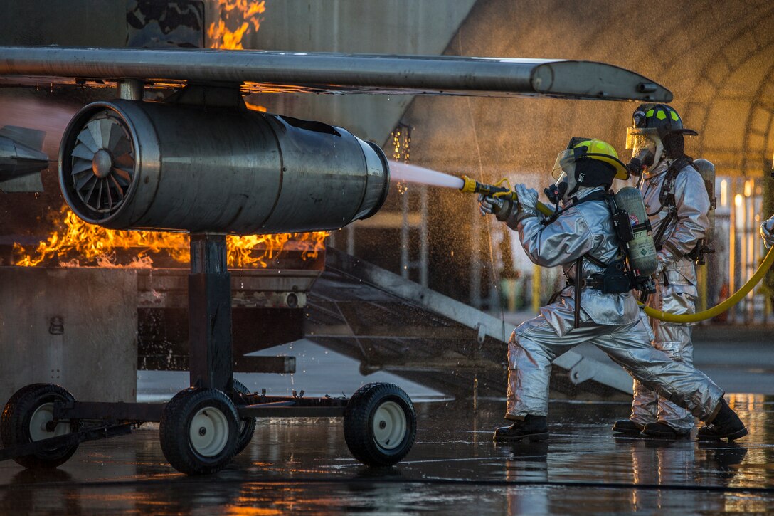 U.S. Marines with Aircraft Rescue and Firefighting (ARFF), Headquarters and Headquarters Squadron (H&HS), Marine Corps Air Station (MCAS) Yuma conduct hand line drills during live burn training on MCAS Yuma, Ariz., June 25, 2019. Hand line drills focus on techniques to push fuel fires away from aircraft, ARFF Marines train monthly to enhance their readiness when responding to emergencies on the flight line. (U.S. Marine Corps photo by Lance Cpl. John Hall)