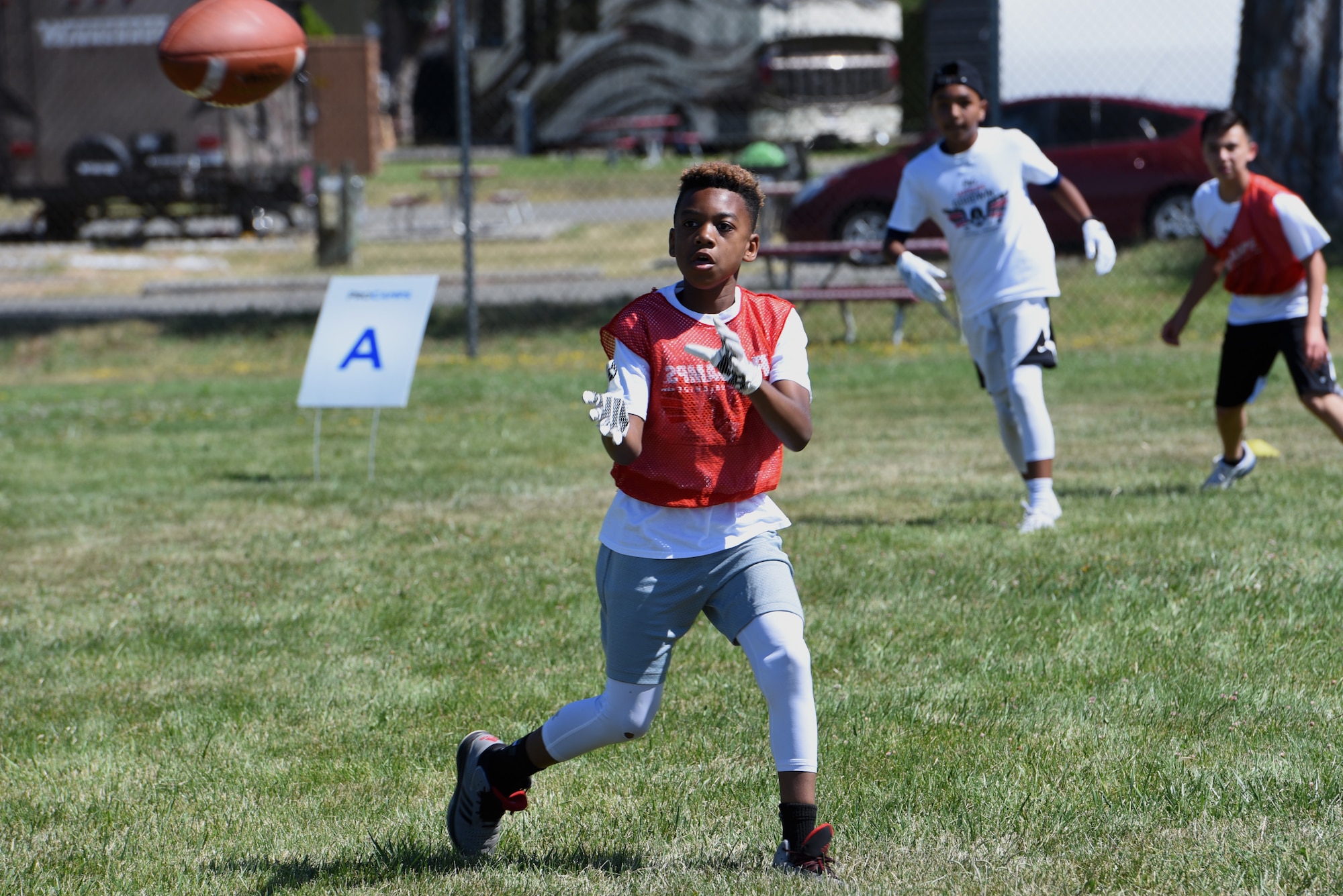 A child catches a pass during a youth football ProCamp June 19, 2019, at Travis Air Force Base, California. The camp was sponsored by Procter & Gamble and the Defense Commissary Agency. Marquise Goodwin, San Francisco 49ers wide receiver, taught the young athletes about football, teamwork and respect. (U.S. Air Force photo by Airman 1st Class Cameron Otte)