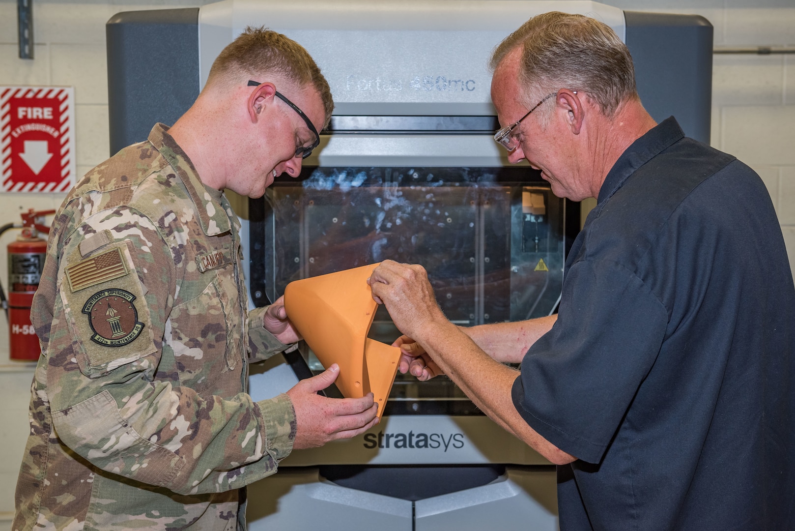 Staff Sgt. Cameron Canupp and Steven Conway, both of 412th Maintenance Squadron, visually inspects a part manufactured in a 3D printer at Edwards Air Force Base, California. (U.S. Air Force photo by Matthew Williams)