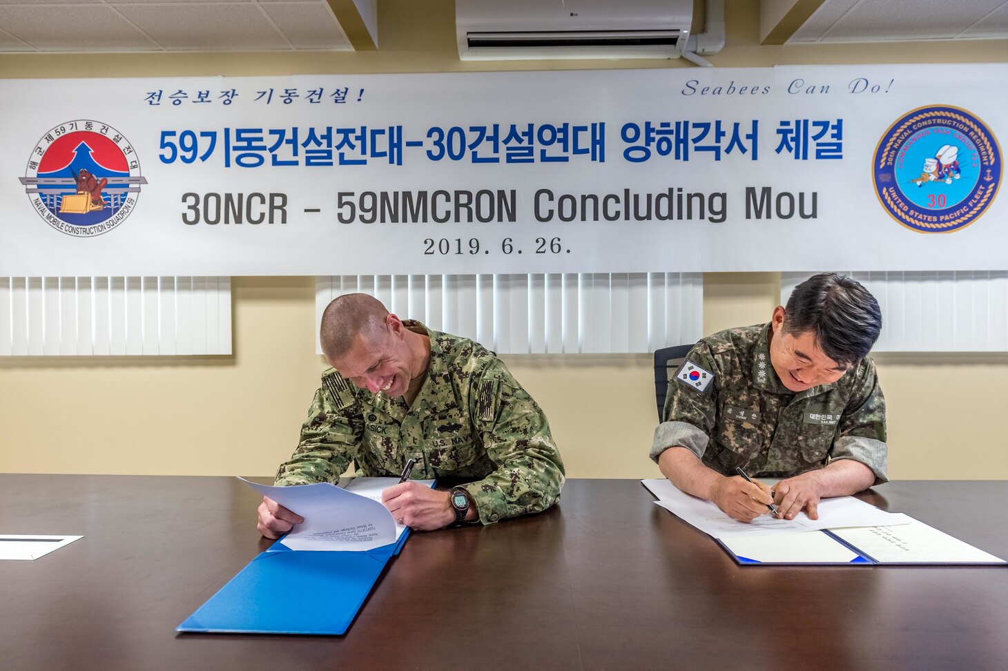 SANTA RITA, Guam (June 26, 2019) Capt. Steve Stasick, Commodore 30th Naval Construction Regiment (30 NCR) and Republic of Korea Navy Capt. Seok Han Yoon, Commodore Naval Mobile Construction Squadron (NMCRON) 59, sign a memorandum of understanding between the two units. The MOU is designed to strengthen the naval engineering capabilities between 30 NCR and NMCRON 59, leading to a tighter operational relationship that will prepare both units for any future contingency