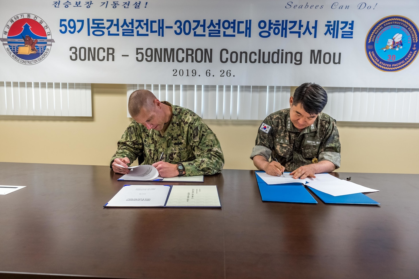 SANTA RITA, Guam (June 26, 2019) Capt. Steve Stasick, Commodore 30th Naval Construction Regiment (30 NCR) and Republic of Korea Navy Capt. Seok Han Yoon, Commodore Naval Mobile Construction Squadron (NMCRON) 59, sign a memorandum of understanding between the two units. The MOU is designed to strengthen the naval engineering capabilities between 30 NCR and NMCRON 59, leading to a tighter operational relationship that will prepare both units for any future contingency.