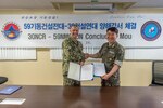 SANTA RITA, Guam (June 26, 2019) Capt. Steve Stasick, Commodore 30th Naval Construction Regiment (30 NCR) and Republic of Korea Navy Capt. Seok Han Yoon, Commodore Naval Mobile Construction Squadron (NMCRON) 59, shake hands following the signing of a memorandum of understanding between the two units. The MOU is designed to strengthen the naval engineering capabilities between 30 NCR and NMCRON 59, leading to a tighter operational relationship that will prepare both units for any future contingency.