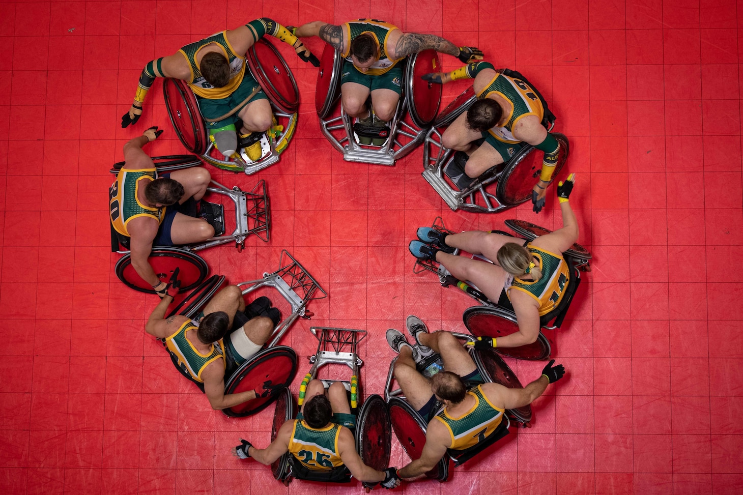 Overhead photo of Team Australia Wounded Warriors huddle in a circle at half time during the 2019 DoD Warrior Games wheelchair rugby preliminaries in Tampa, Florida.