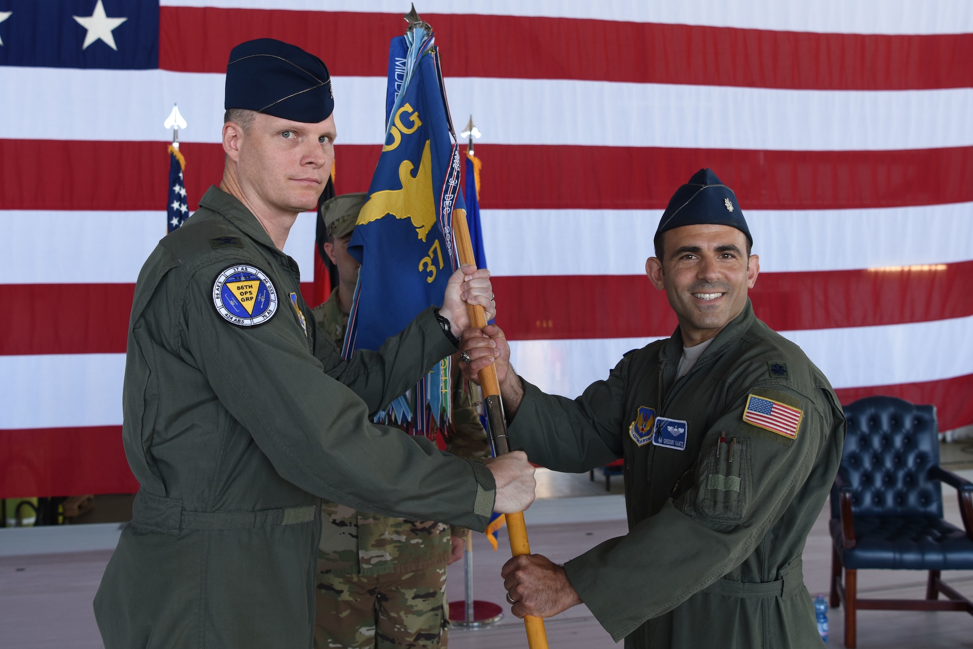 U.S. Air Force Col. James G. Young, 86th Operations Group commander, passes a guidon to Lt. Col. Gregory P. Kantz, 37th Airlift Squadron commander, during a change of command on Ramstein Air Base, Germany, June, 24, 2019. During the event, Kantz took command of the 37th AS from Lt. Col. Jonathan B. Cato.