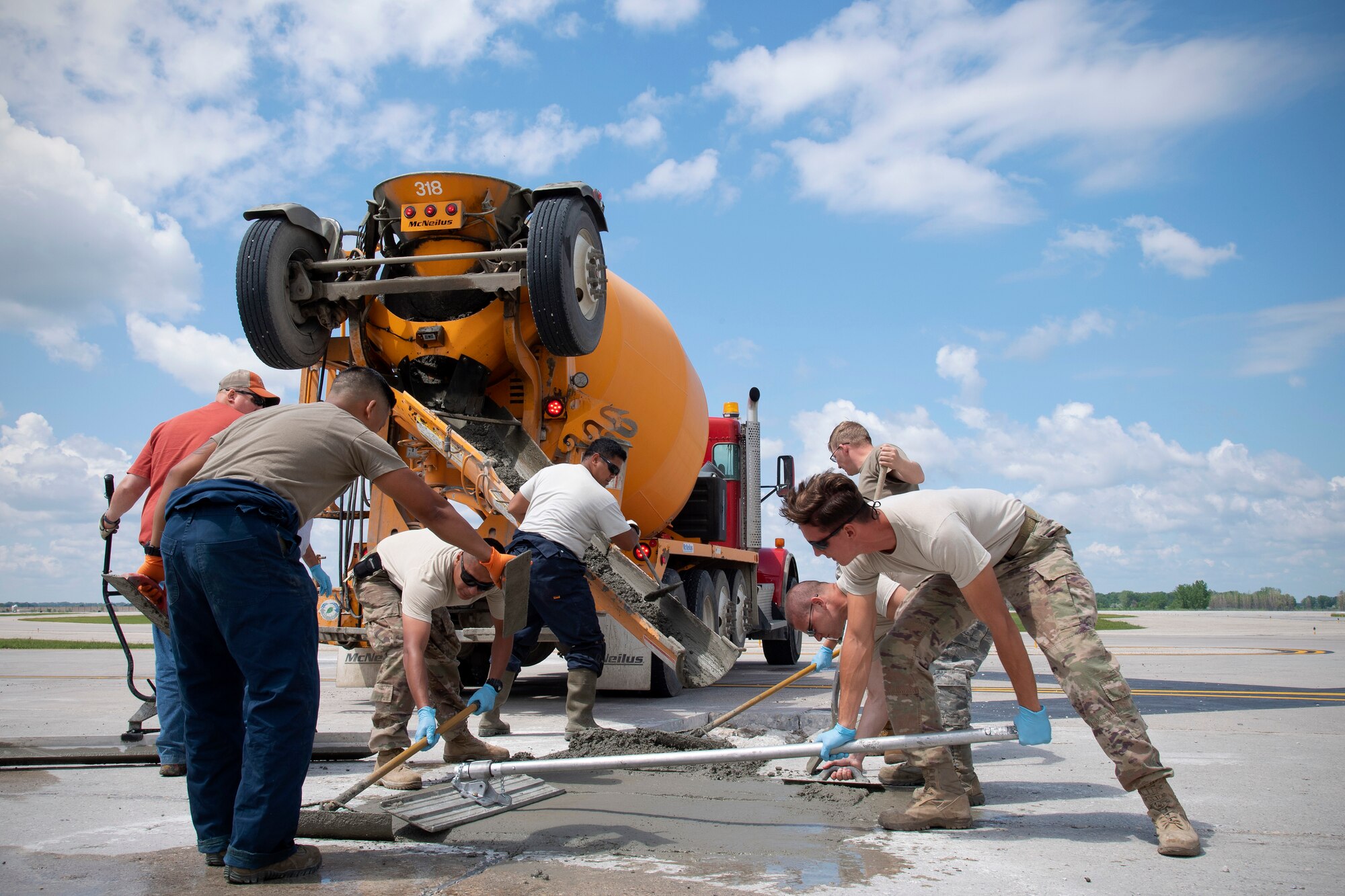 Members with 319th Civil Engineer Squadron horizontal construction work together quickly to fill a premade hole in the flightline June 25, 2019, on Grand Forks Air Force Base, North Dakota. The team of airmen and civilians began their extensive project by cutting out and jackhammering selected areas of the flightline, and will complete the project following the concrete pour. (U.S. Air Force photo by Senior Airman Elora J. Martinez)
