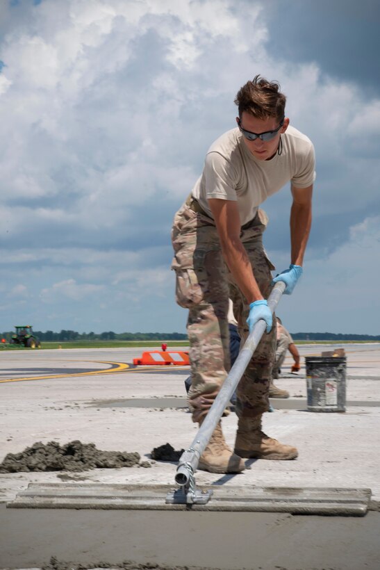 Senior Airman Brody Powell, 319th Civil Engineer Squadron construction and pavement journeyman, smooths over freshly-poured concrete on the flightline June 25, 2019, on Grand Forks Air Force Base, North Dakota. The 319 CES construction and pavement shop is responsible for horizontal construction during the warmer months, and mission-essential snow removal during the winter. (U.S. Air Force photo by Senior Airman Elora J. Martinez)