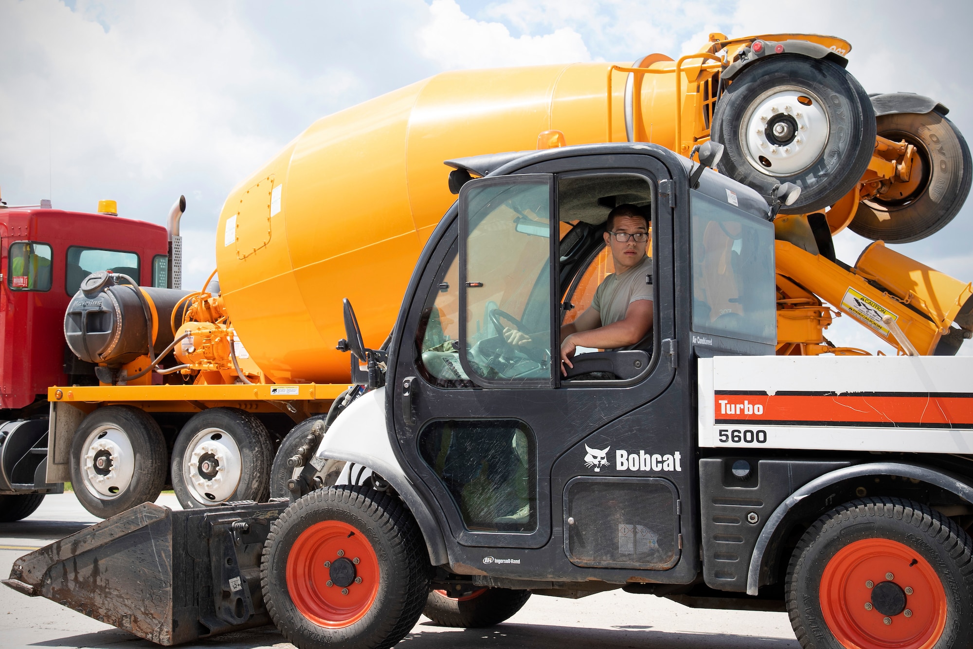 Senior Airman Adrian Castaneda, 319th Civil Engineer Squadron construction and pavement journeyman, reverses a Toolcat 5600 June 25, 2019, on Grand Forks Air Force Base, North Dakota. Castaneda transported excess cement back and forth on the job site using the Toolcat, ensuring the concrete-pouring operation went smoothly. (U.S. Air Force photo by Senior Airman Elora J. Martinez)