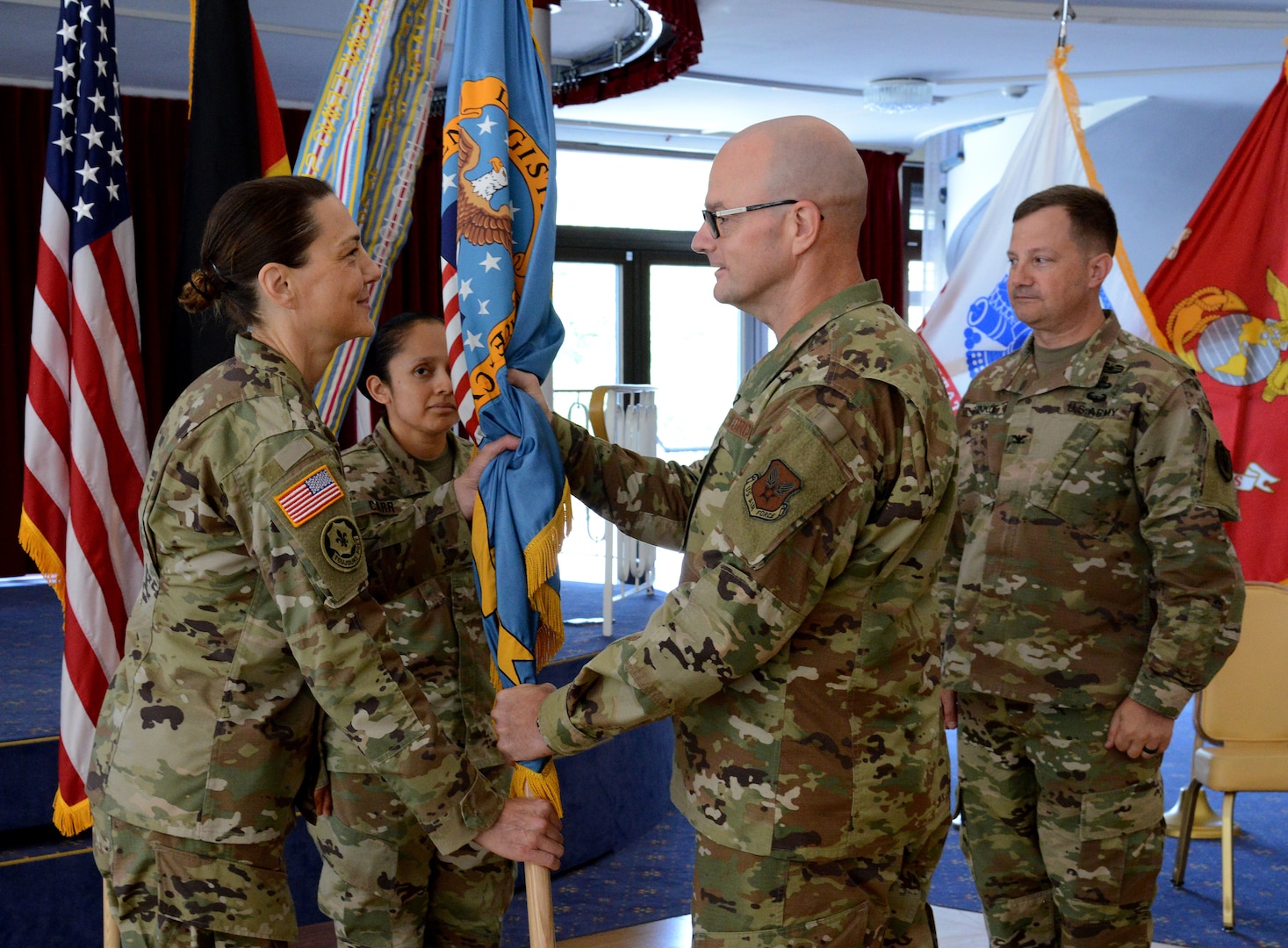 Air Force Maj. Gen. Allan Day, DLA Logistics Operations director, presents the colors to Army Col. Krista Hoffman, incoming DLA Europe & Africa commander, during a change of command ceremony June 26 in Kaiserslautern, Germany, as Army Master Sgt. Roxanna Carr (middle left), DLA E&A senior enlisted leader, and Army Col. Theodore Shinkle (right), outgoing commander, look on.