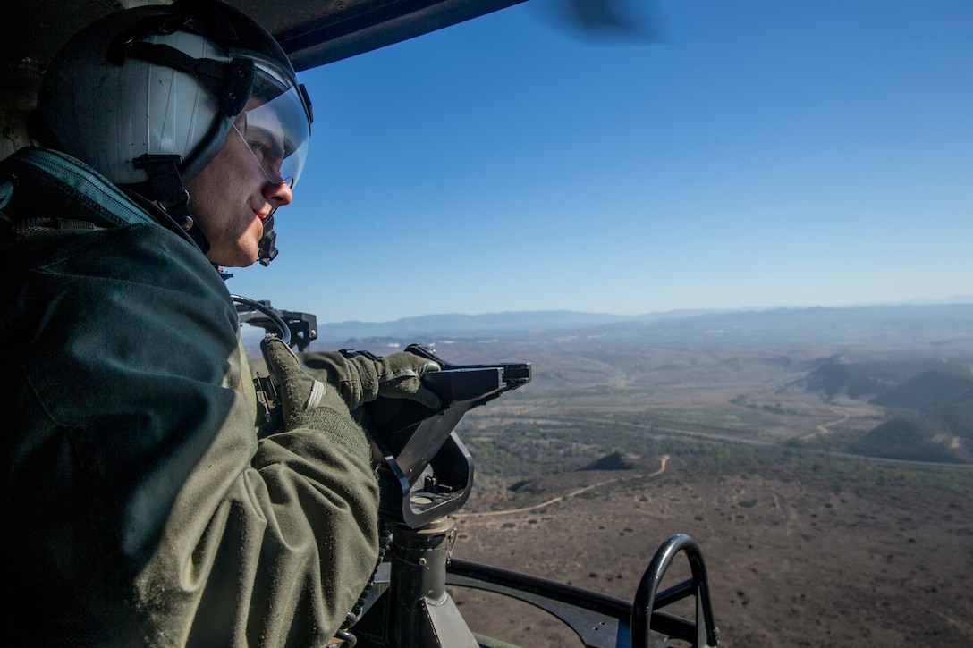 U.S. Marine Corps Lance Cpl. Alexander Cobzaru, a crew chief with Marine Light Attack Helicopter Training Squadron (HMLAT) 303, Marine Aircraft Group 39, 3rd Marine Aircraft Wing, observes the flight path from the gunner’s seat of a UH-1Y Venom helicopter during flight operations at Marine Corps Air Station Camp Pendleton, California, Oct. 31, 2018. Marines with HMLAT-303 routinely conduct day and night training flights in order to maintain readiness among pilots and crew members. (U.S. Marine Corps photo by Lance Cpl. Drake Nickels)