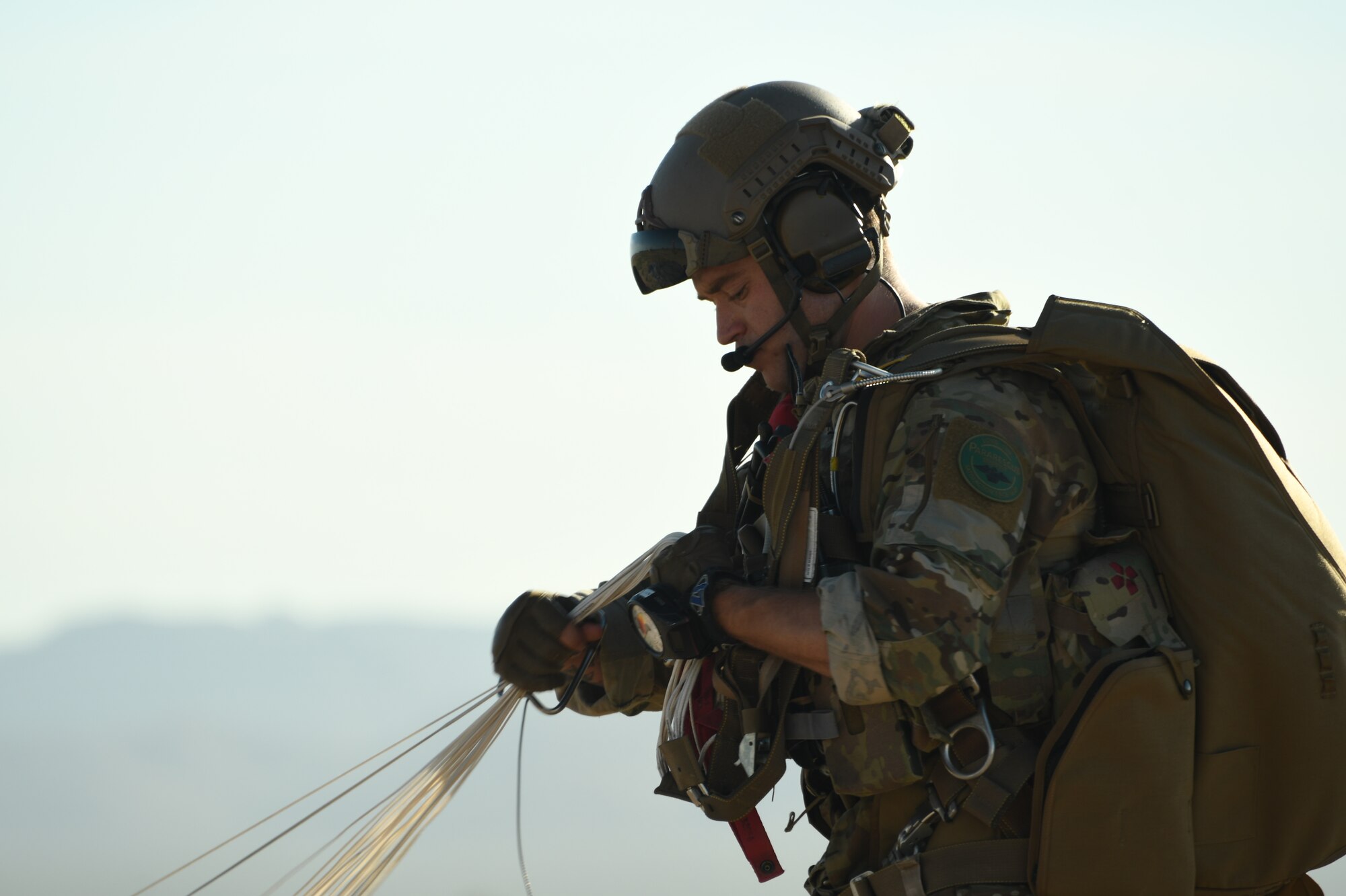 A U.S. Air Force pararescueman gathers his parachute after landing in a drop zone at the Marana Regional Airport, Ariz., June 26th, 2019.