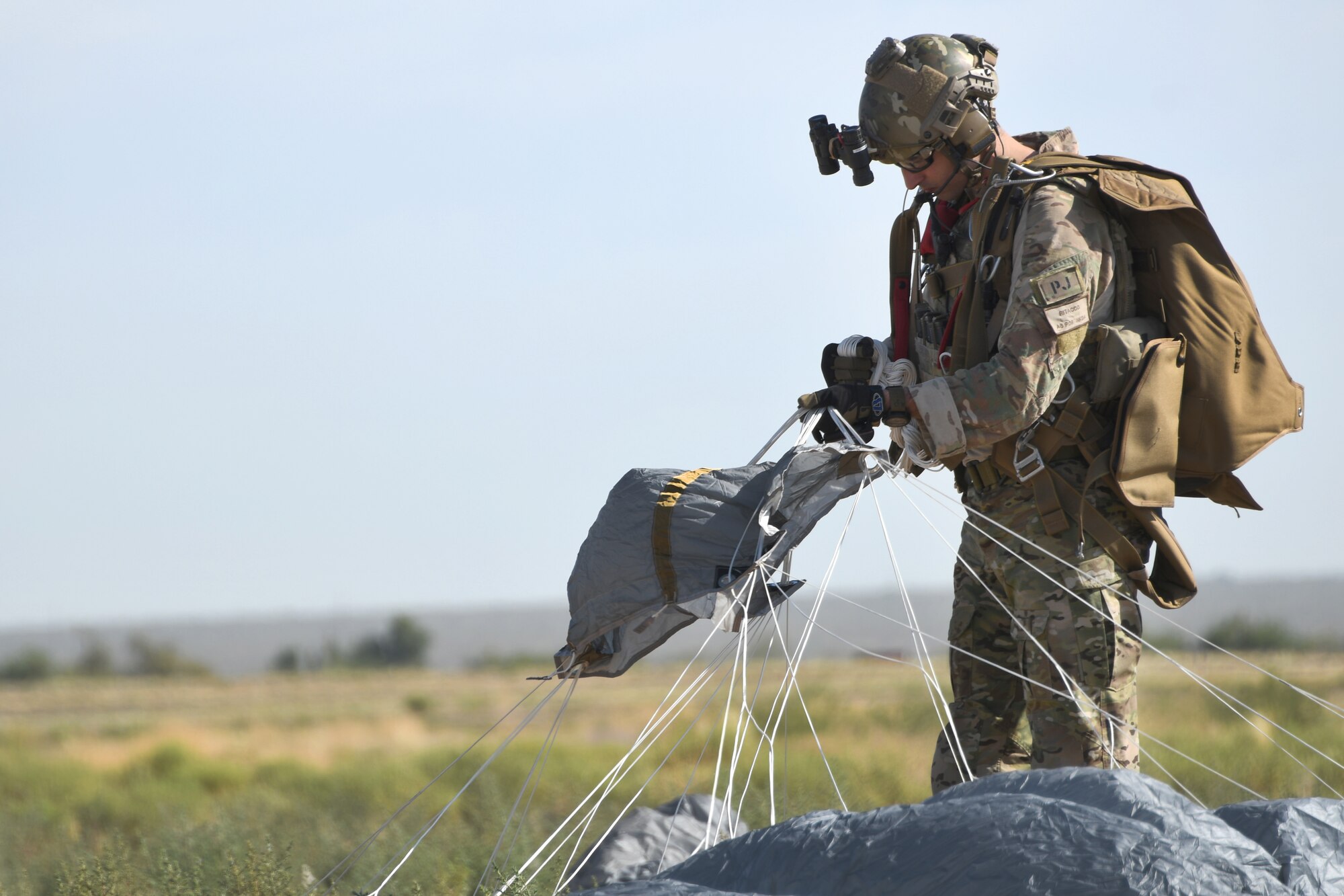 A U.S. Air Force pararescueman gathers his parachute after landing in a drop zone at the Marana Regional Airport, Ariz., June 26th, 2019.