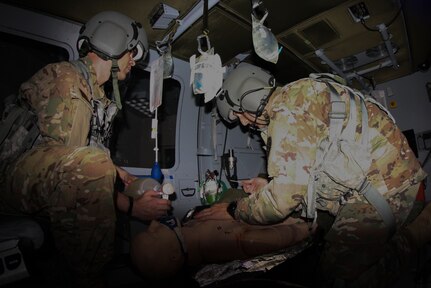 Two physicians experience the challenge of providing en route care in the Combat Flight Medic Helicopter Simulator June 11 during the 2019 Joint Emergency Medicine Exercise.