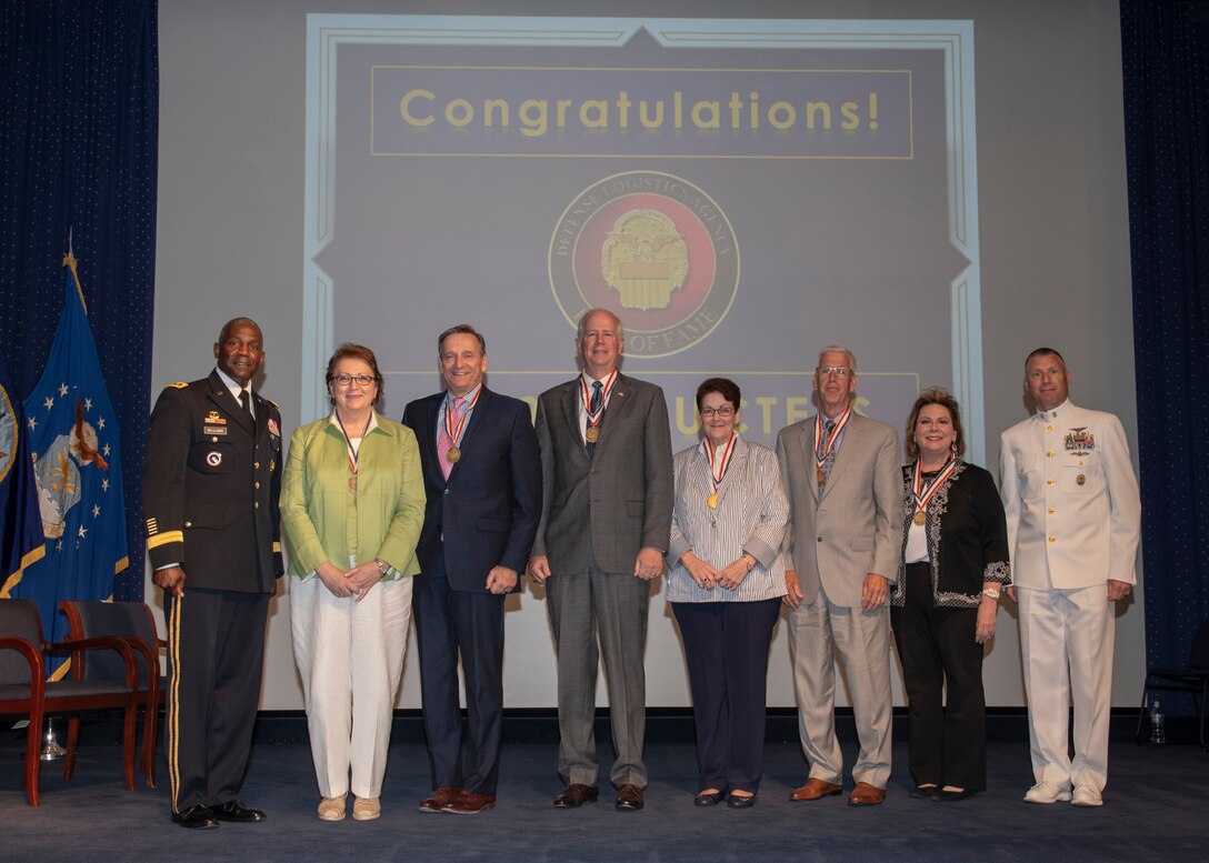 Two military officers pose with three men and three women during the DLA Hall of Fame ceremony.