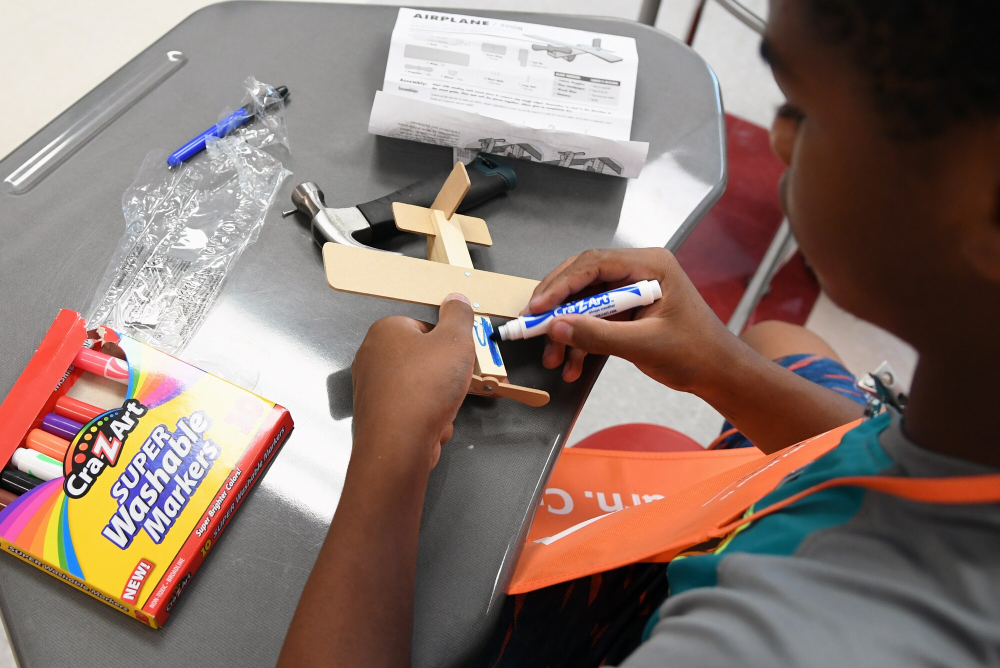 Kaleb Foggie, Biloxi Junior High School eighth-grader, colors a wooden airplane after assembly during the Biloxi Public Schools Science, Technology, Engineering and Mathematics Summer Camp program at Biloxi High School in Biloxi, Mississippi, June 25, 2019. The four-day STEM summer program teaches first through seventh grade students skills for future careers and fosters valuable life skills like problem solving, creativity and collaboration. Keesler personnel volunteered their time to lead instructions on various projects. (U.S. Air Force photo by Kemberly Groue)