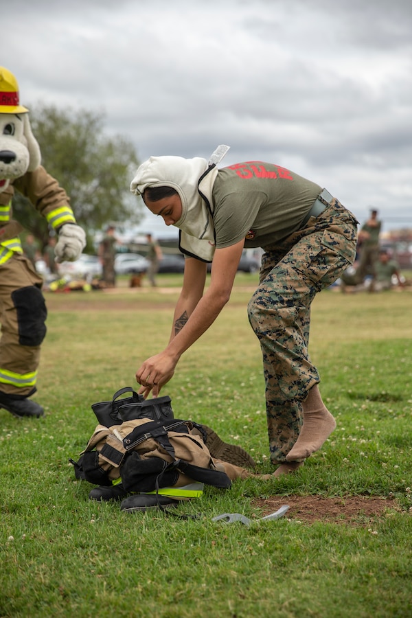 Lance Cpl. Stephanie Reina-Mata, a marine with Miramar Aircraft Rescue and Firefighting (ARFF), puts on her gear in her part of the ARFF rodeo relay competition at Marine Corps Air Station Miramar, Calif., June 22. The ARFF rodeo is an annual event held by H&HS to build unit cohesion and boost morale through various competitions between different ARFF units. (U.S. Marine Corps photo by Lance Cpl. Cheng Chang)