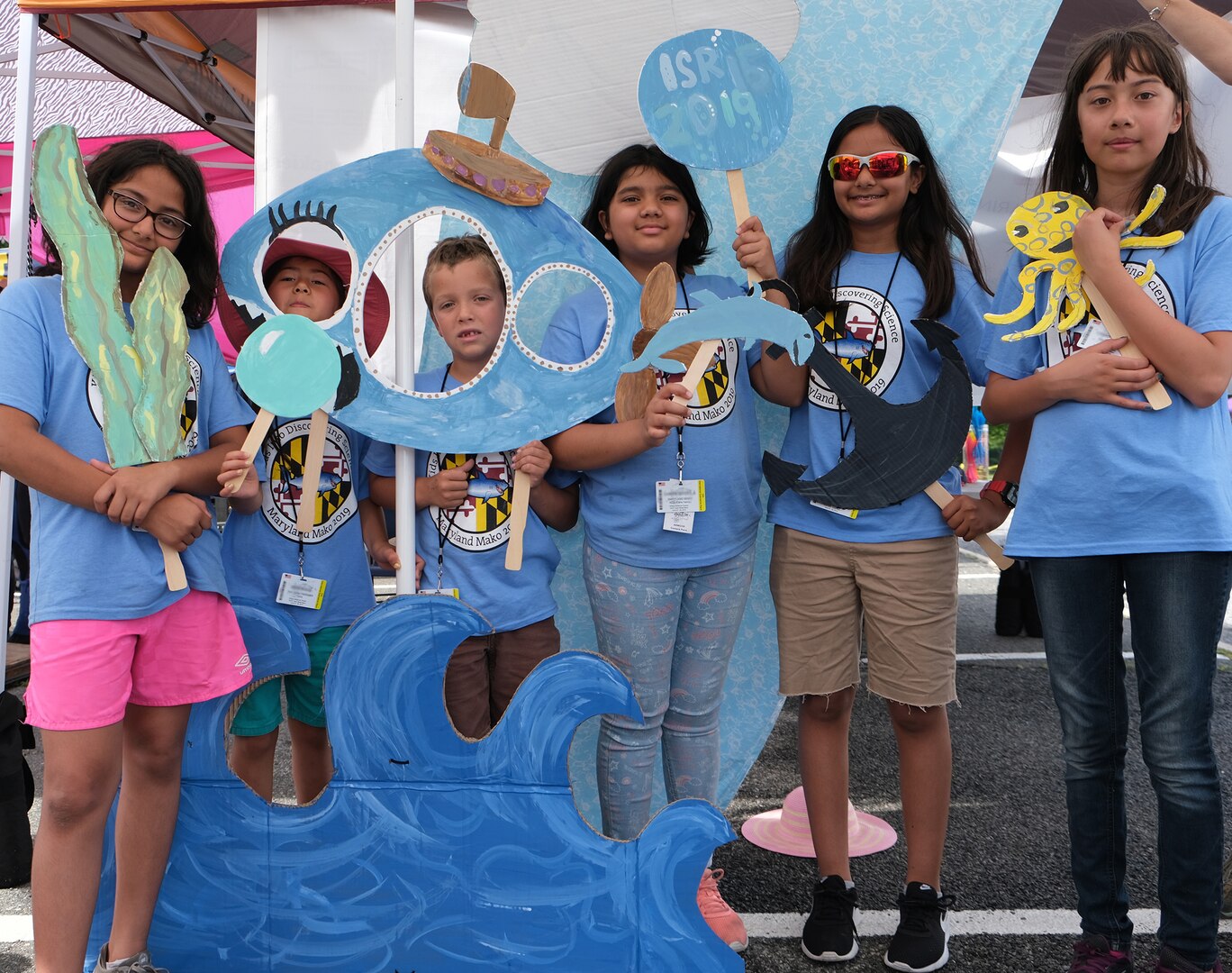 Team members from the Kids into Discovering Science program in Maryland pose with their handmade props for the photo booth under their tent at the 15th International Human-Powered Submarine Races on June 25, 2019.
