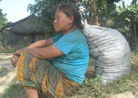 IMAGE: A woman in Beldangi-I camp in a deep look by resting on the sack of briquettees coals given for cooking purpose.