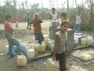 IMAGE: Refugees filling up vessels with water in camps