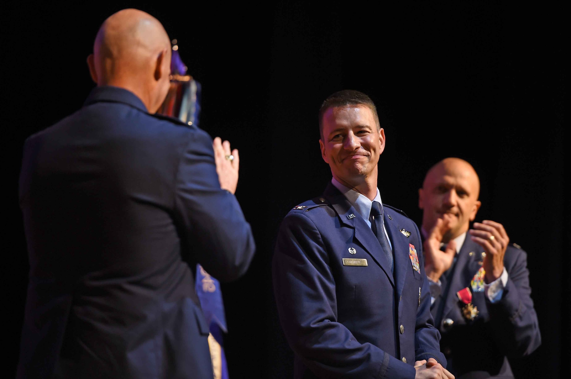 Four Airmen stand on stage during a ceremony