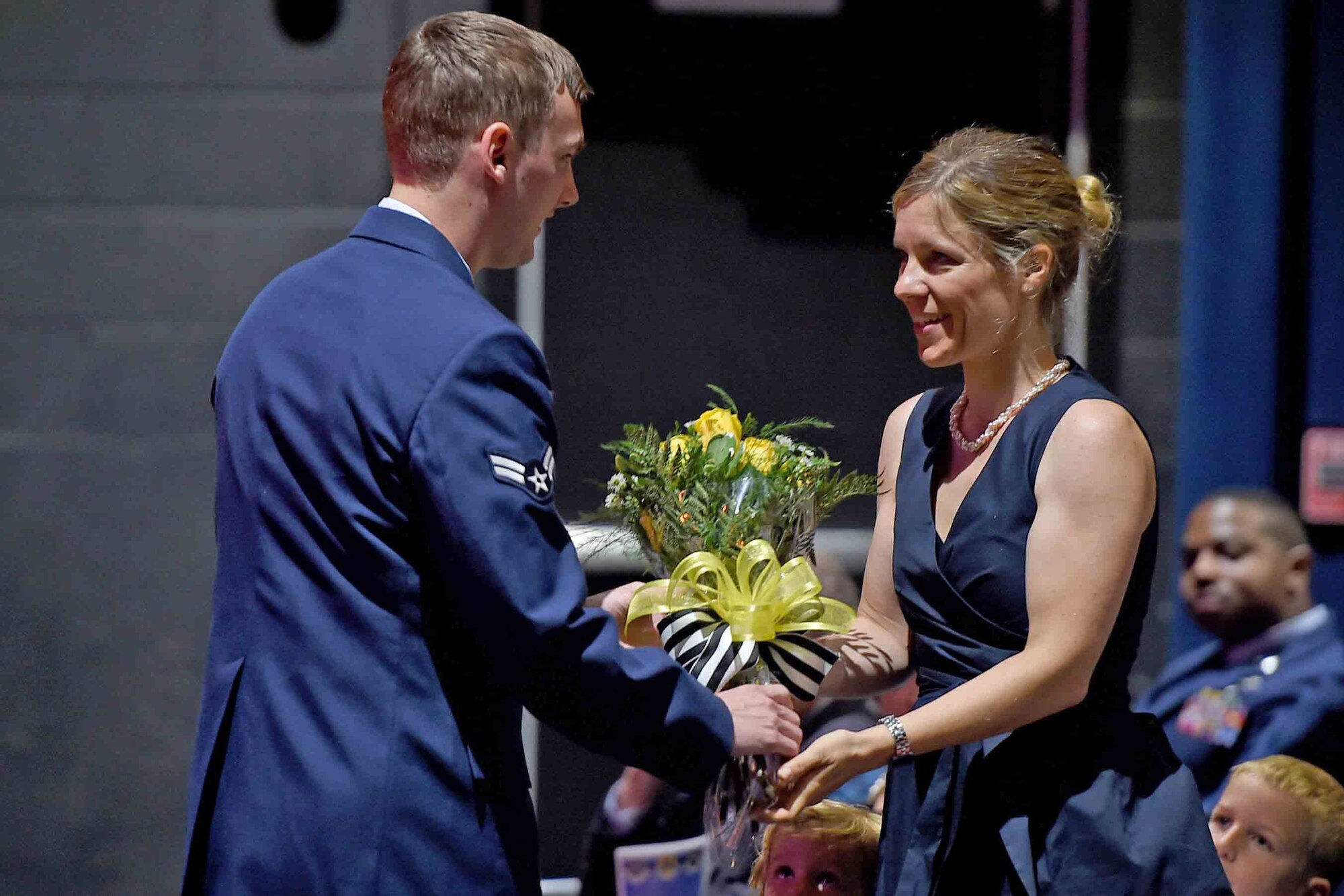 An Airman hands flowers to the new commnaders wife.