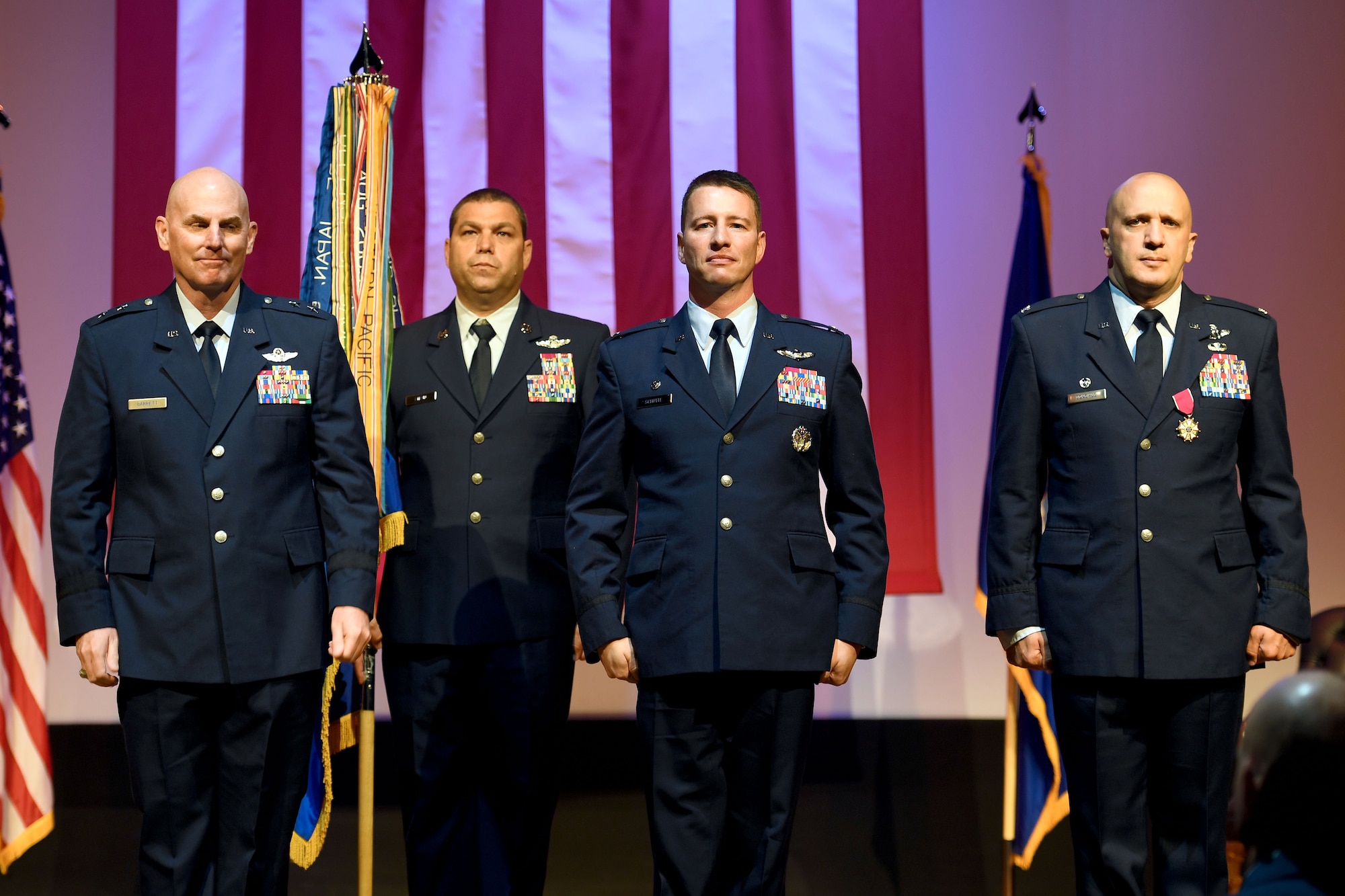 Four Airmen stand on stage during a ceremony