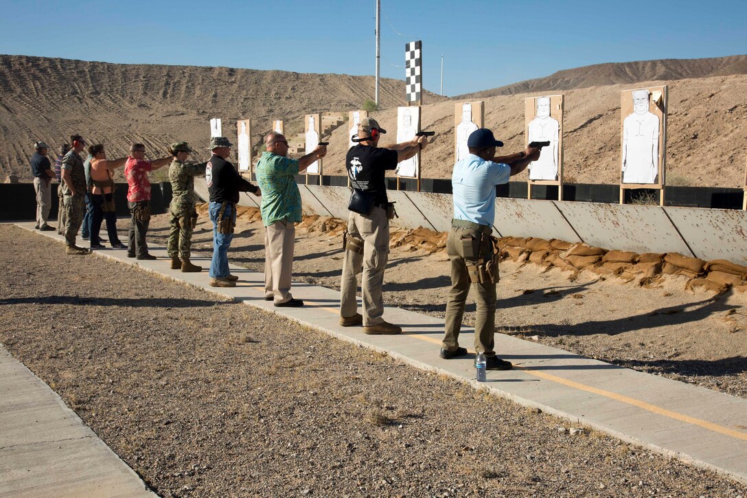 Directors from all departments aboard Marine Corps Logistics Base Barstow, California, fire away from the five yard line at silhouette targets during the Commander’s Executive Pistol Challenge,June 20. Range Safety Officer Sgt. Kenneth Mullins keeps a watchful eye on the shooters.