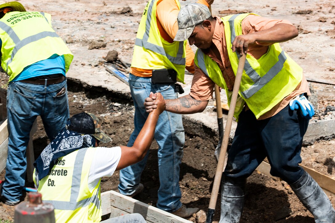 Louis Quiroga, right, construction worker, helps Jose Robles, construction worker, climb out of a catch basin during a storm-drain construction project, June 25, 2019, at Moody Air Force Base, Ga. This construction will benefit the base by alleviating flooding, preventing deterioration and erosion and saving money.(U.S. Air Force photo by Senior Airman Erick Requadt)