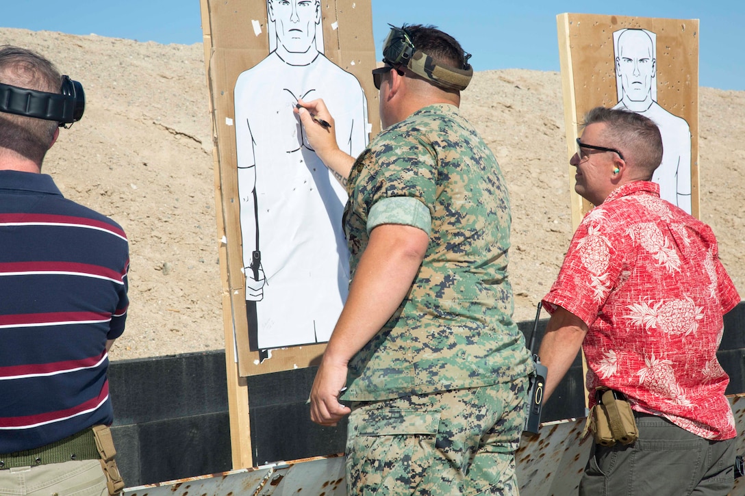 Staff Sgt. Nicholas Hensley, range officer in charge, scores Base Executive Officer Lt. Col. Timothy Silkowski's target during the Commander's Executive Pistol Challenge, June 20. Silkowski ended the competition as the best shot in the group.
